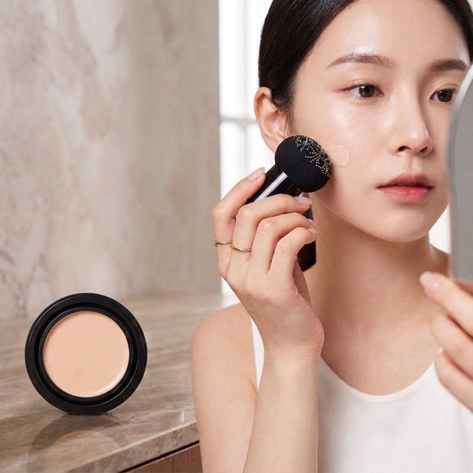 Woman applying mushroom head air cushion foundation on cheek with sponge applicator