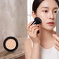 Woman applying mushroom head air cushion foundation on cheek with sponge applicator